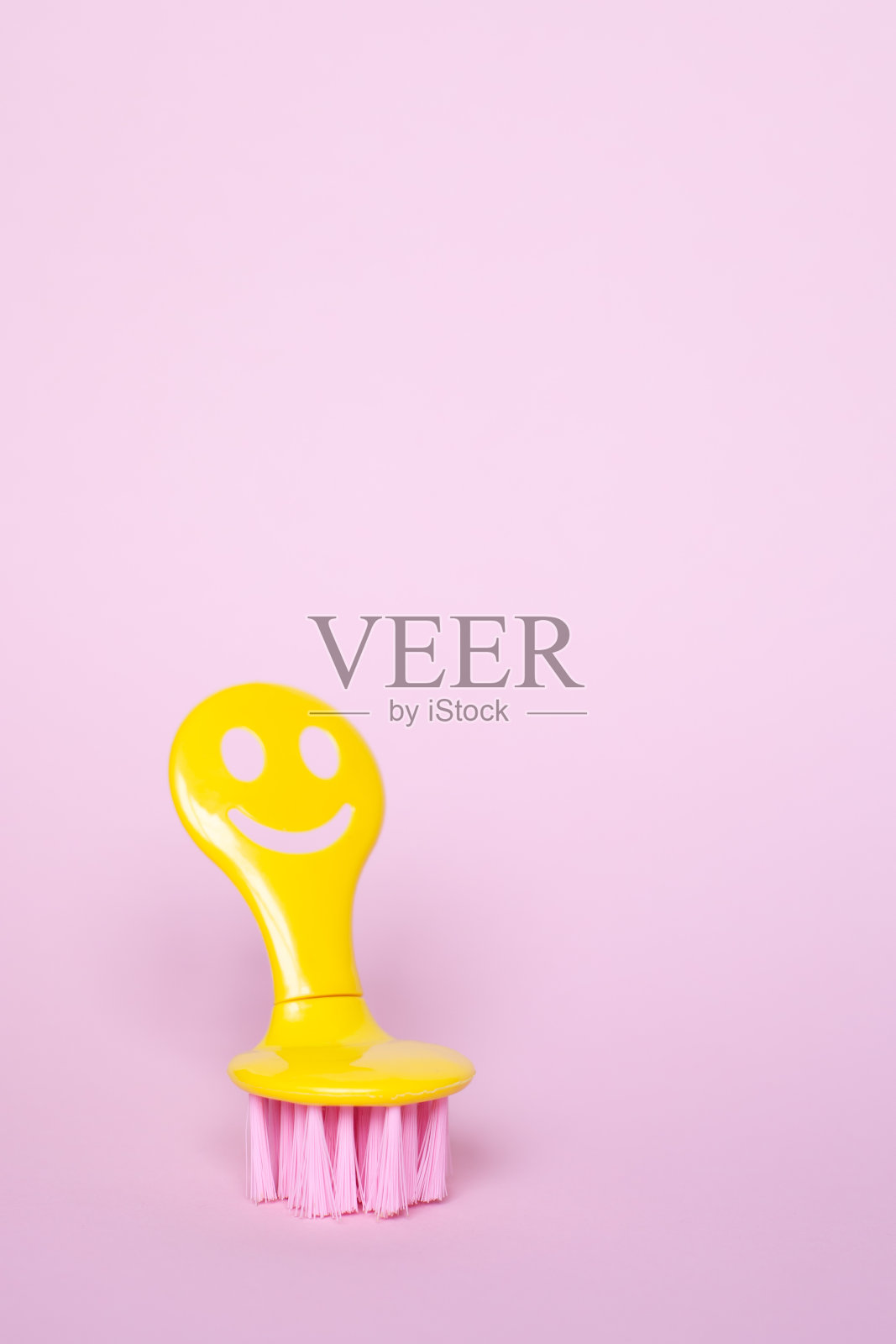 在粉红色的背景上用微笑的黄色笔刷清洗。照片摄影图片