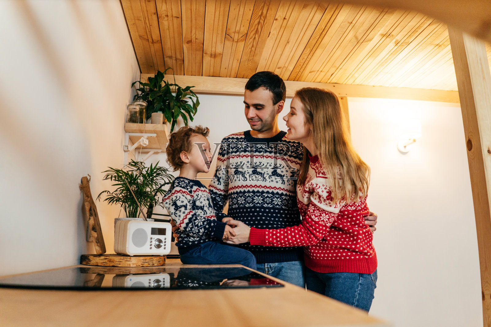 幸福的一家人穿着圣诞毛衣在厨房里。照片摄影图片