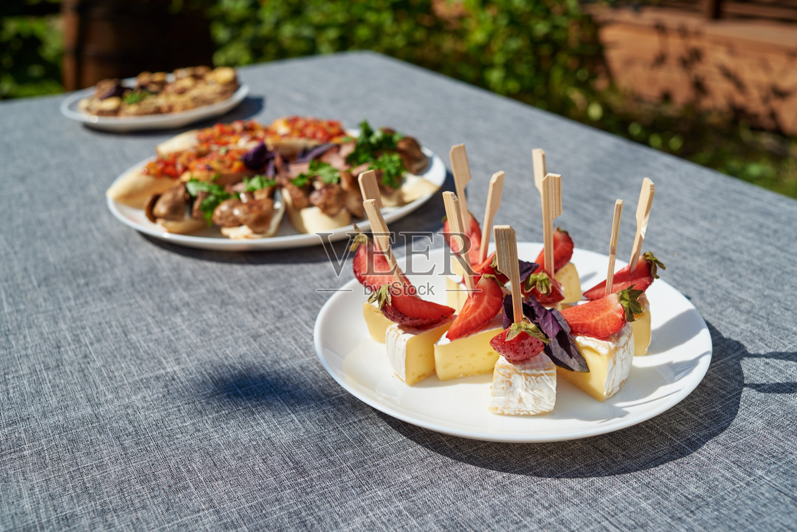 白盘子里有卡门贝尔奶酪布里奶酪和草莓，复制空间。暑假户外招待会。自助餐。盘子里有水果和奶酪照片摄影图片