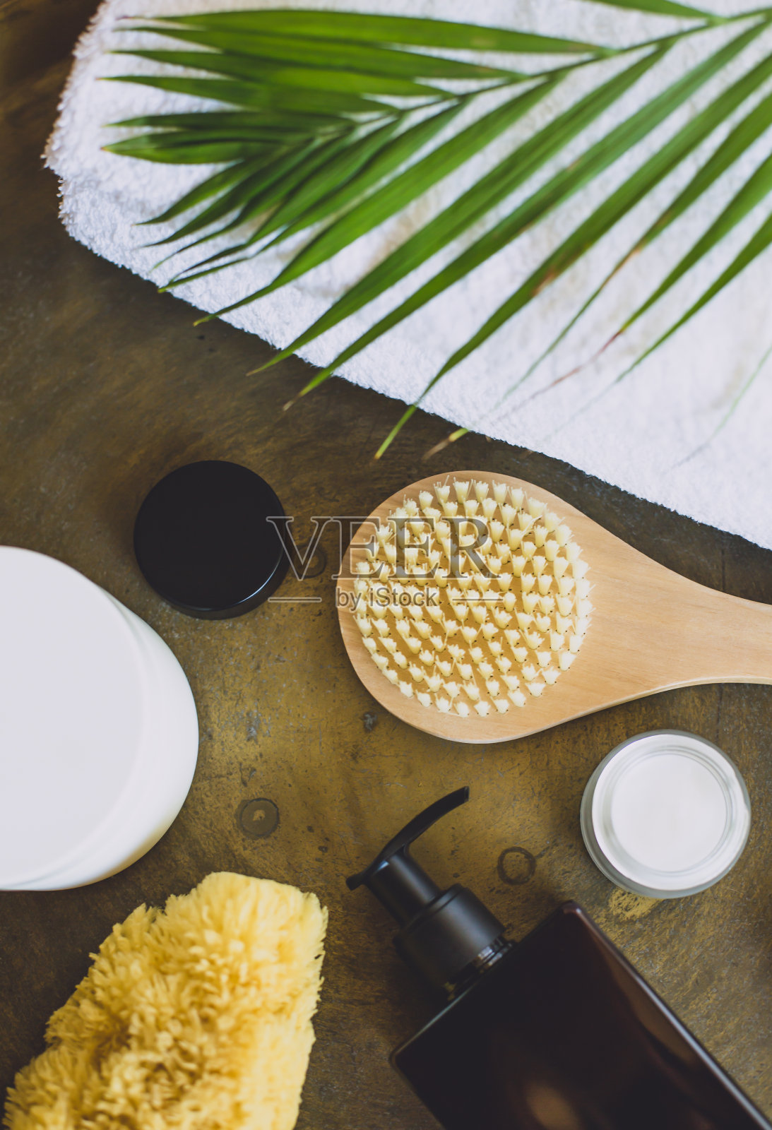 一罐面霜、一把木刷和一块spa海绵被放置在金属表面。照片摄影图片