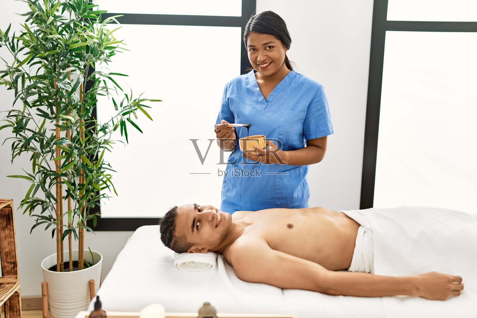 拉丁男子微笑愉快地接受美容中心的面部护理。照片摄影图片