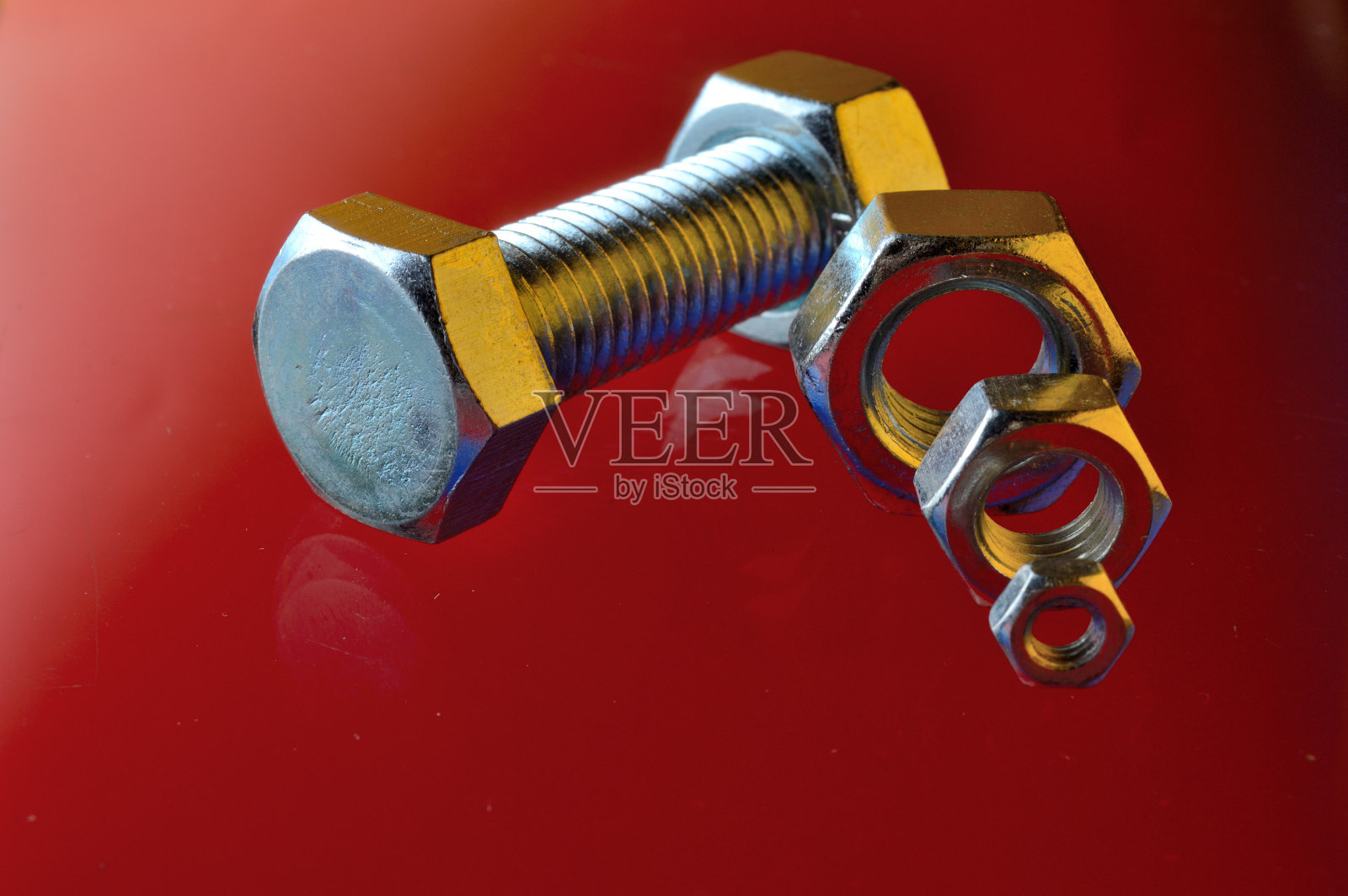 新的，镀铬螺栓和螺母在红色背景。照片摄影图片