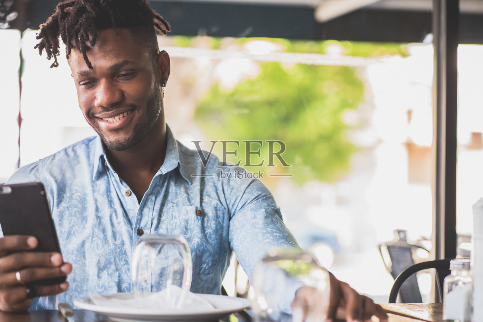 一个年轻人在餐馆里用手机。照片摄影图片