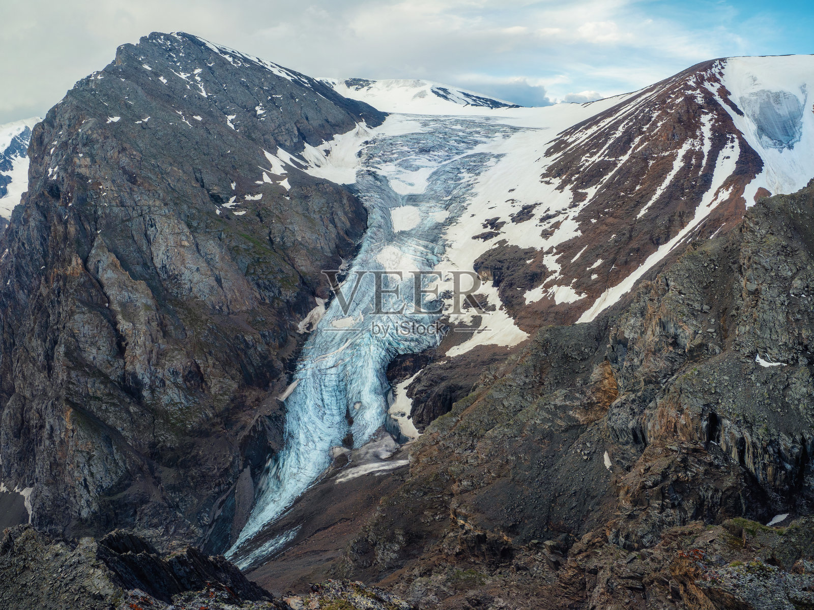 难以到达的大冰川和巨大的雪山。风景优美的高地景观与大开裂的蓝色冰川与划痕之间的冰碛在高雪峰和岩石顶部的背景。照片摄影图片