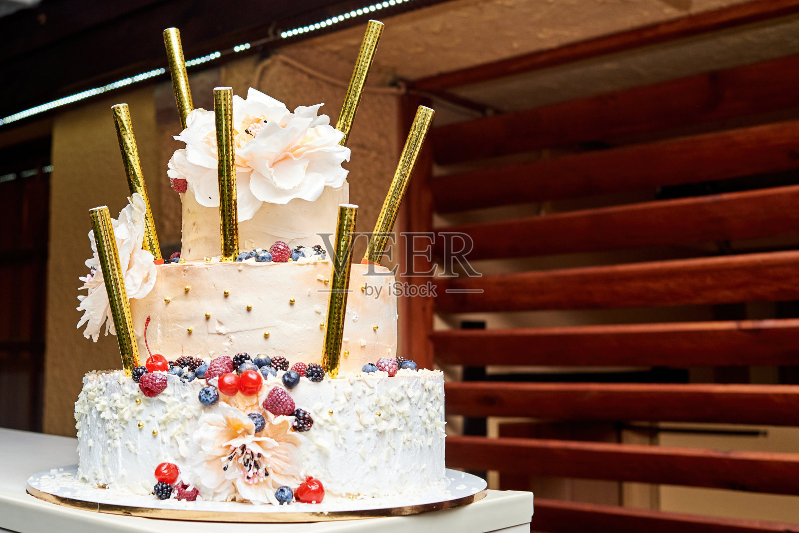 白色多层生日或婚礼蛋糕与鲜花，浆果和孟加拉火。节日的食物照片摄影图片