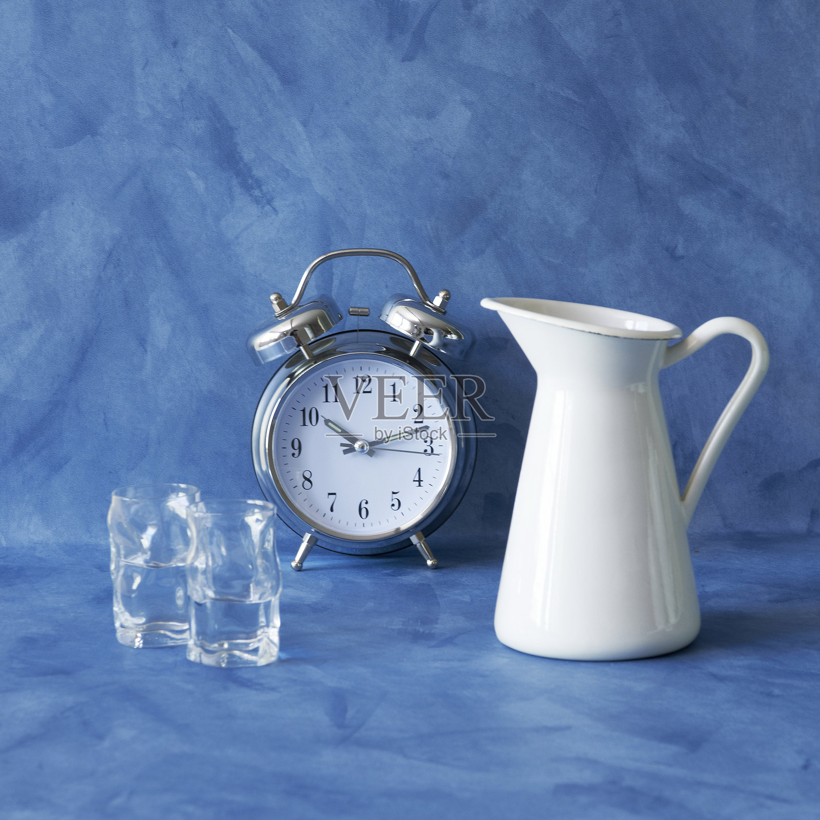 蓝色背景与水玻璃花瓶在时钟照片摄影图片