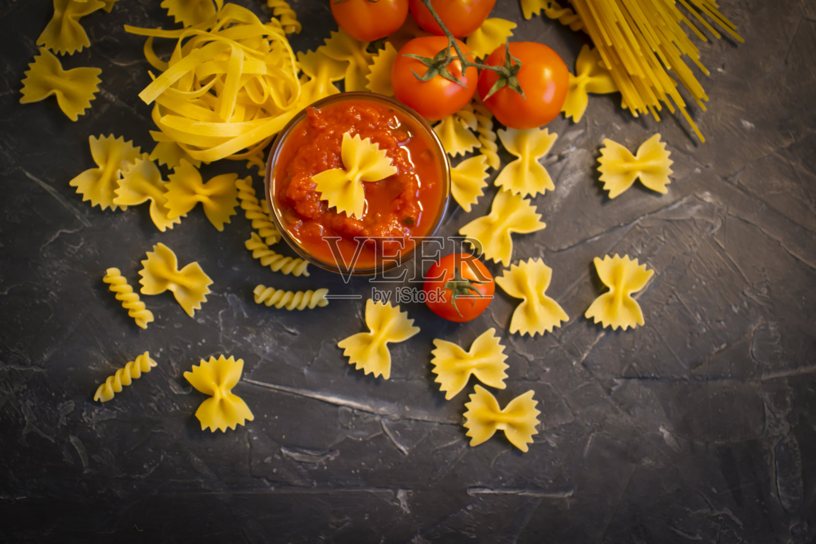 干意大利面，酱汁，西红柿放在混凝土背景上照片摄影图片