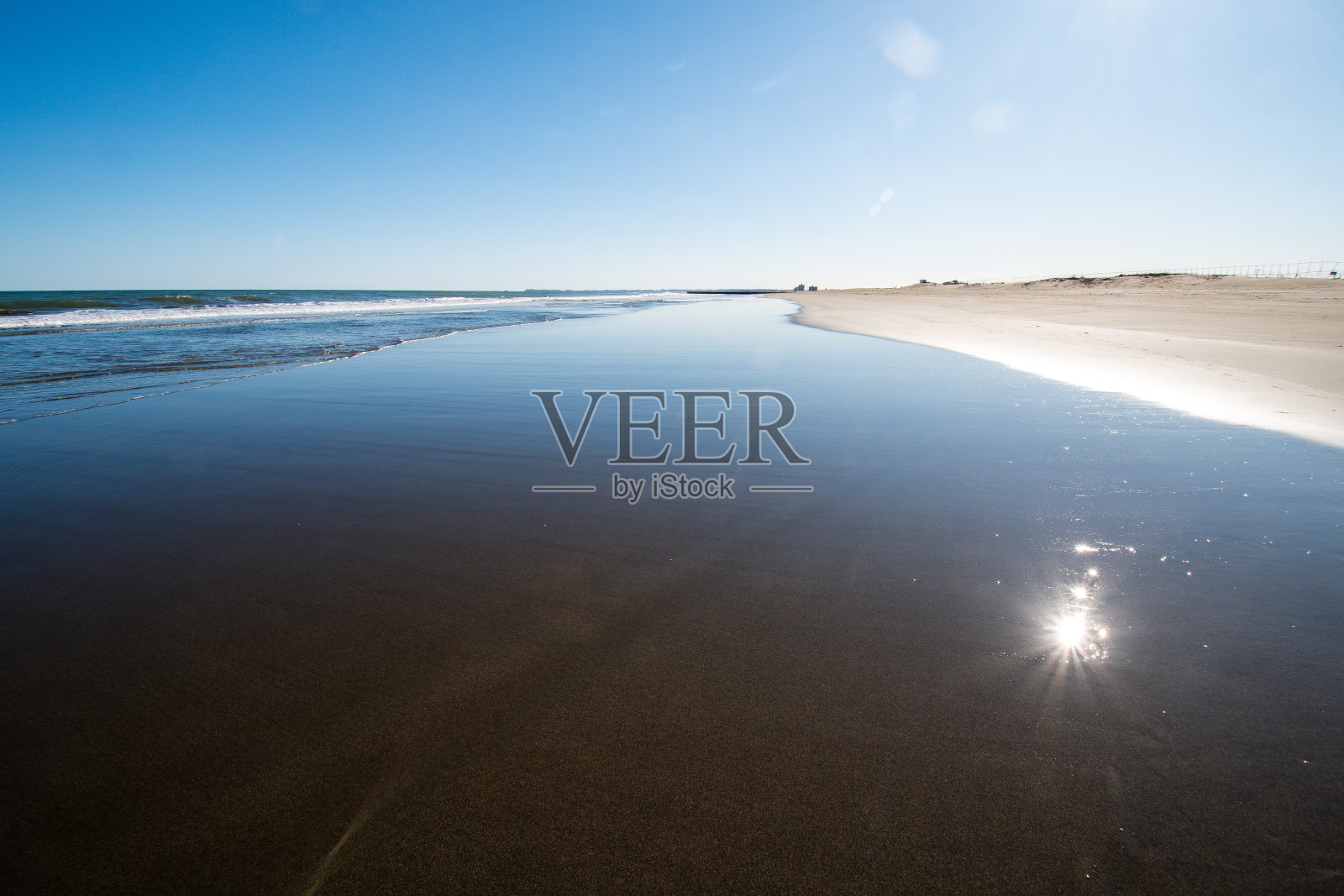 海浪冲刷着海滩，阳光反射在水面上照片摄影图片