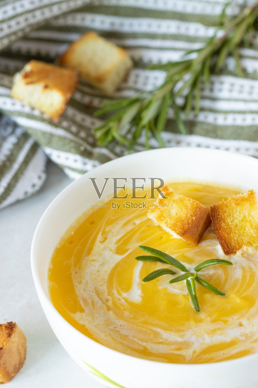南瓜汤配奶油，小麦饼干和新鲜迷迭香，放在白盘子里照片摄影图片