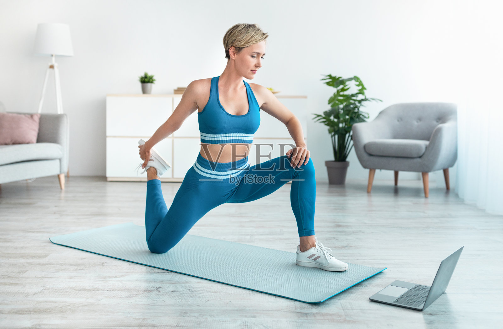 自信的女人用笔记本电脑拉伸腿部肌肉照片摄影图片