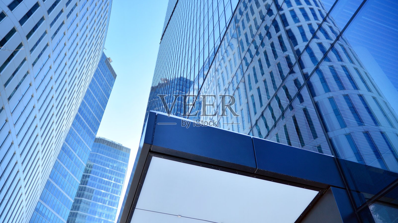 在蓝天下的商业区现代摩天大楼的底部视图。照片摄影图片