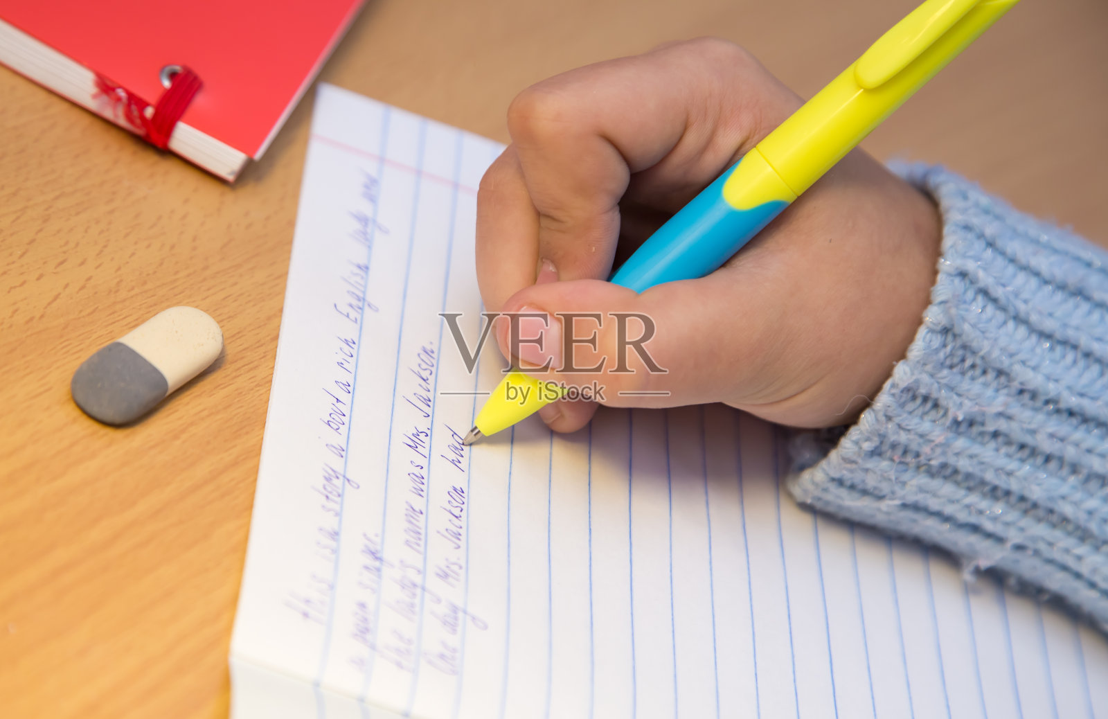 特写镜头的小学生正在用圆珠笔写英语。照片摄影图片