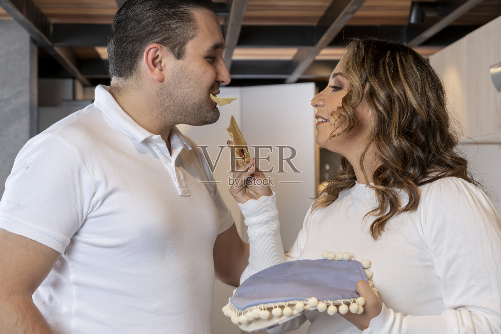 拉丁妇女在准备早餐时给丈夫吃玉米薄饼照片摄影图片