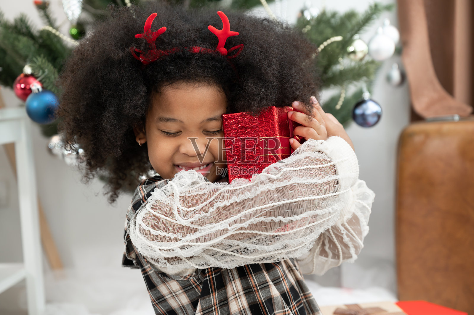 带着礼盒和圣诞装饰品的快乐非洲式发型小女孩照片摄影图片