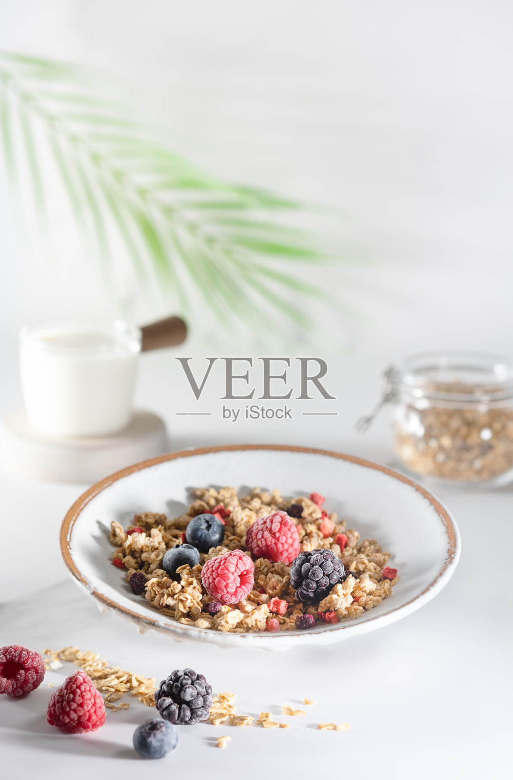 白色大理石桌上的一碗格兰诺拉麦片、酸奶、牛奶、新鲜的树莓、蓝莓、芒果，是一份健康的早餐照片摄影图片
