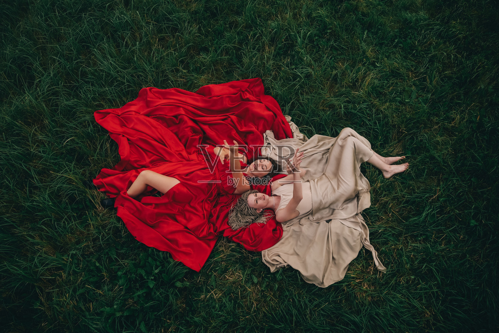 两个穿着长裙躺在草地上的漂亮女人的时尚照片照片摄影图片