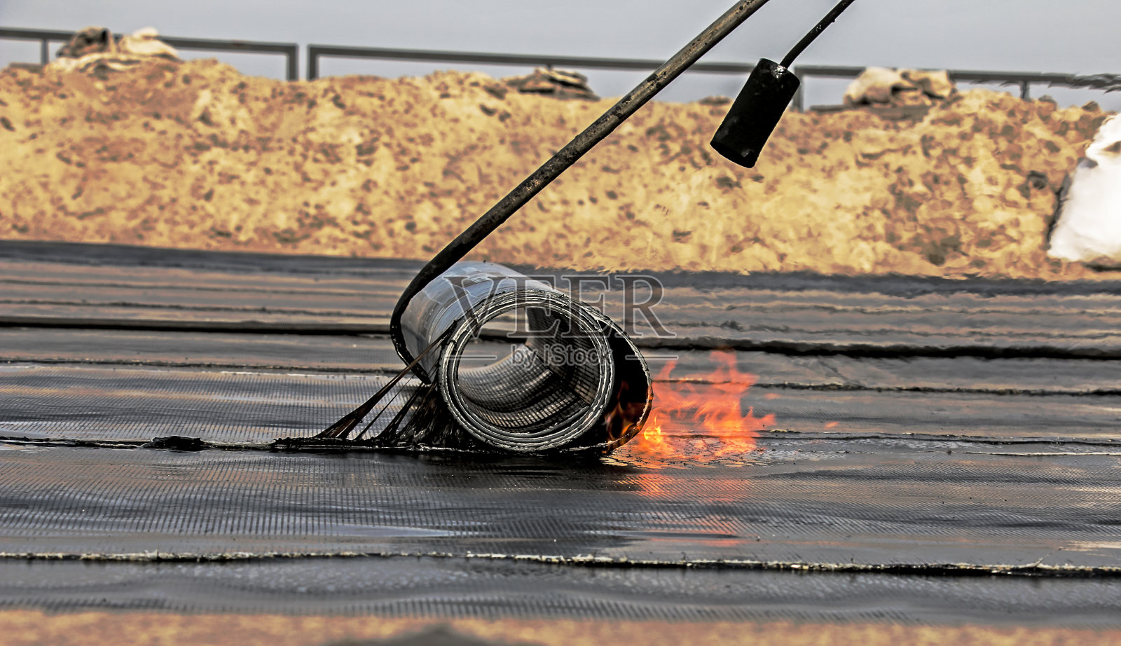 用喷灯安装屋顶材料的过程。沥青毡在安装过程中融化。照片摄影图片