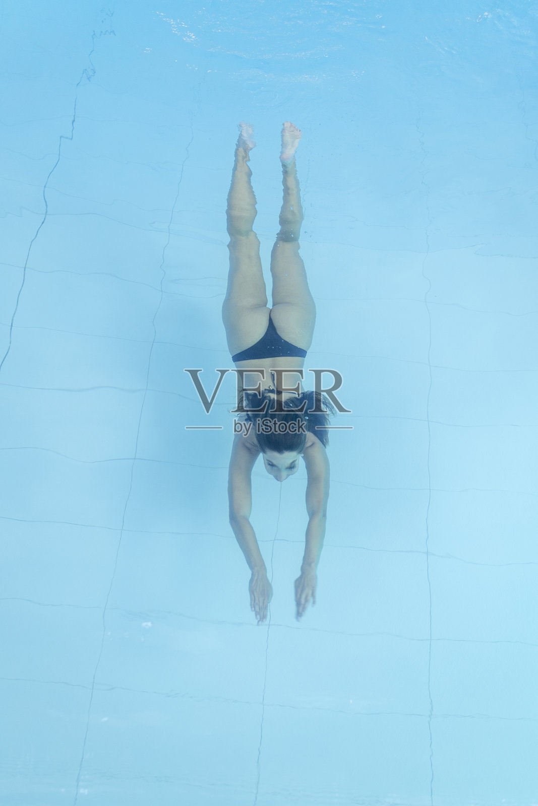 无人机拍摄的年轻女子在蓝色游泳池跳水照片摄影图片