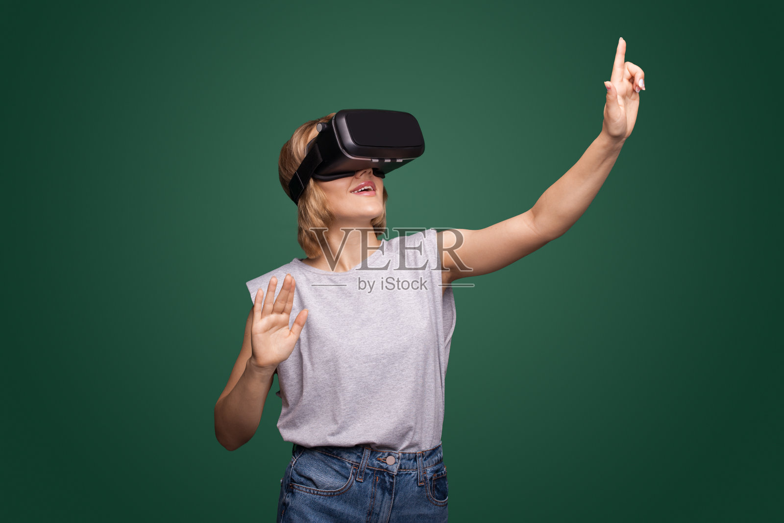 一名女性在工作室的绿色墙壁上测试耳机时的增强现实体验照片摄影图片