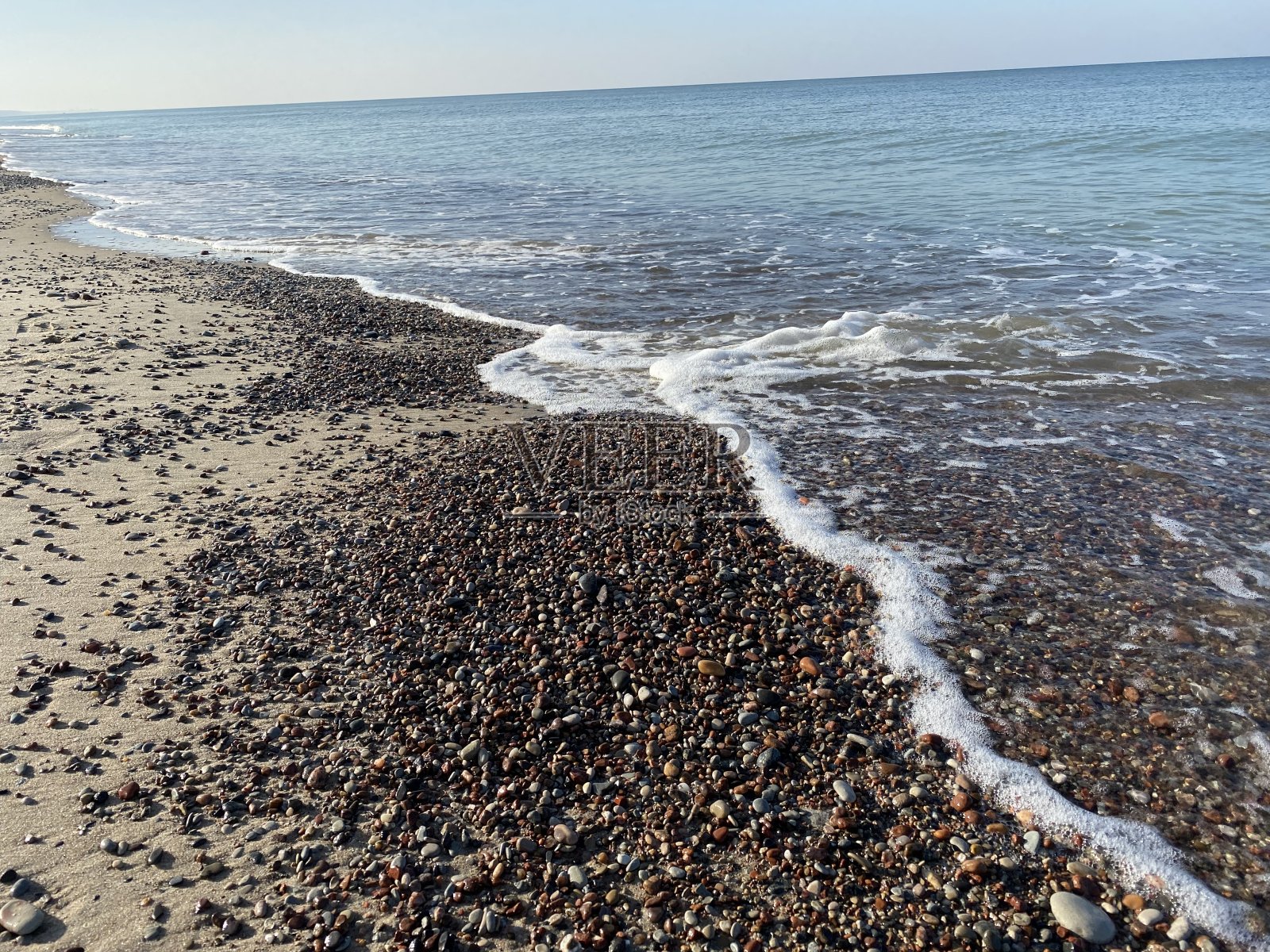 五颜六色的海岩和潮湿的沙子，有水和泡沫。波罗的海沿岸晴天的背景照片摄影图片