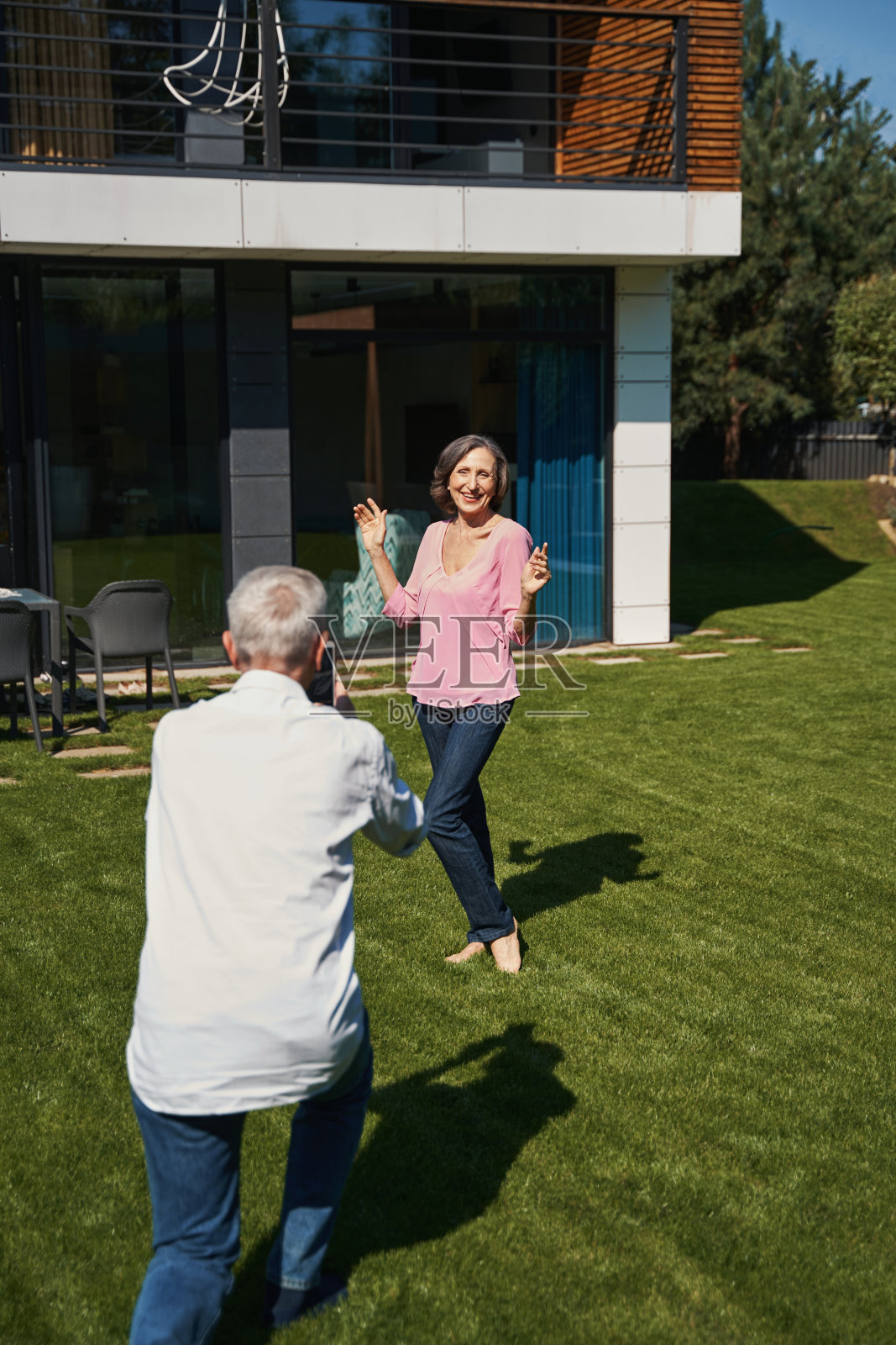快乐的老妇人在房子附近摆姿势拍照照片摄影图片