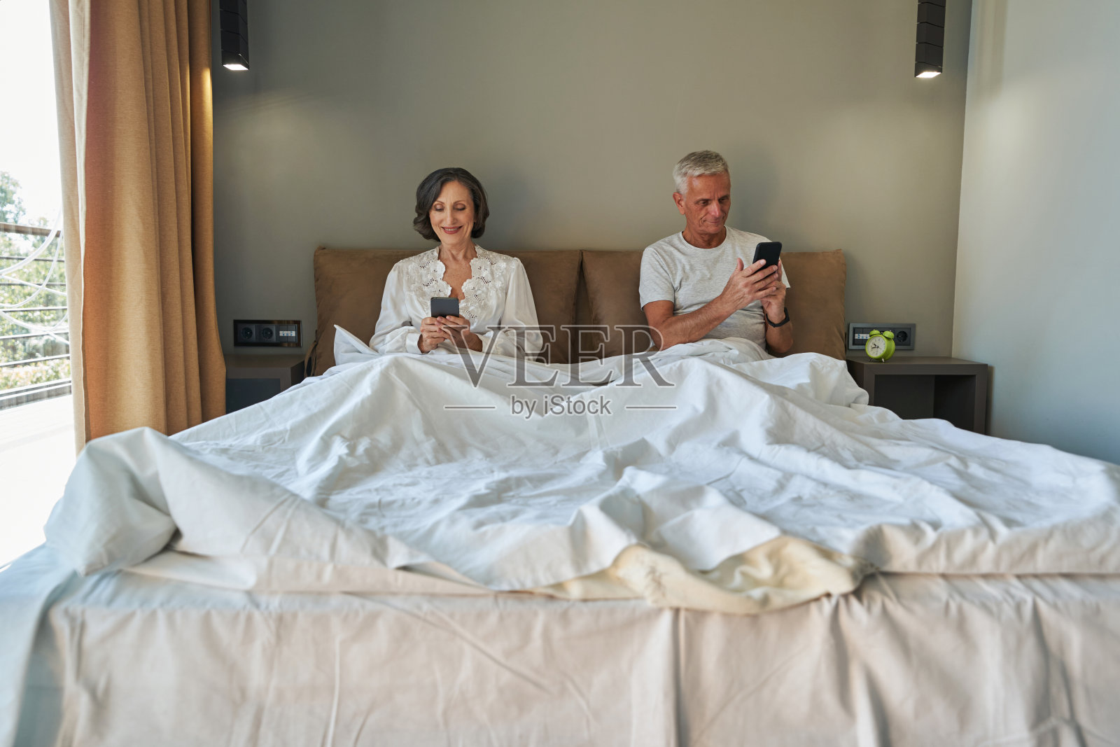 在卧室里使用智能手机的退休老人很高兴照片摄影图片