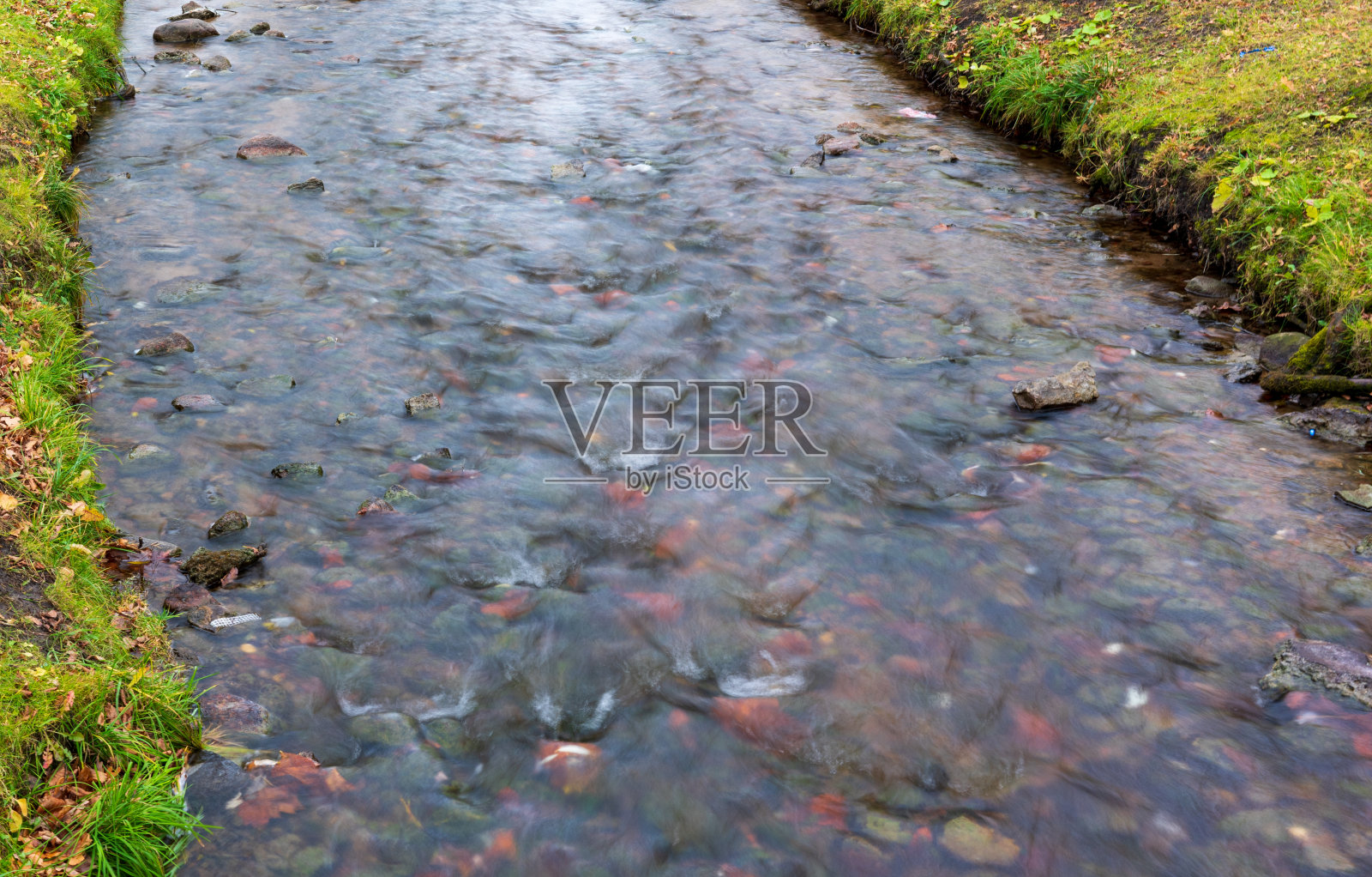 小溪，在绿草的背景上模糊的流水照片摄影图片