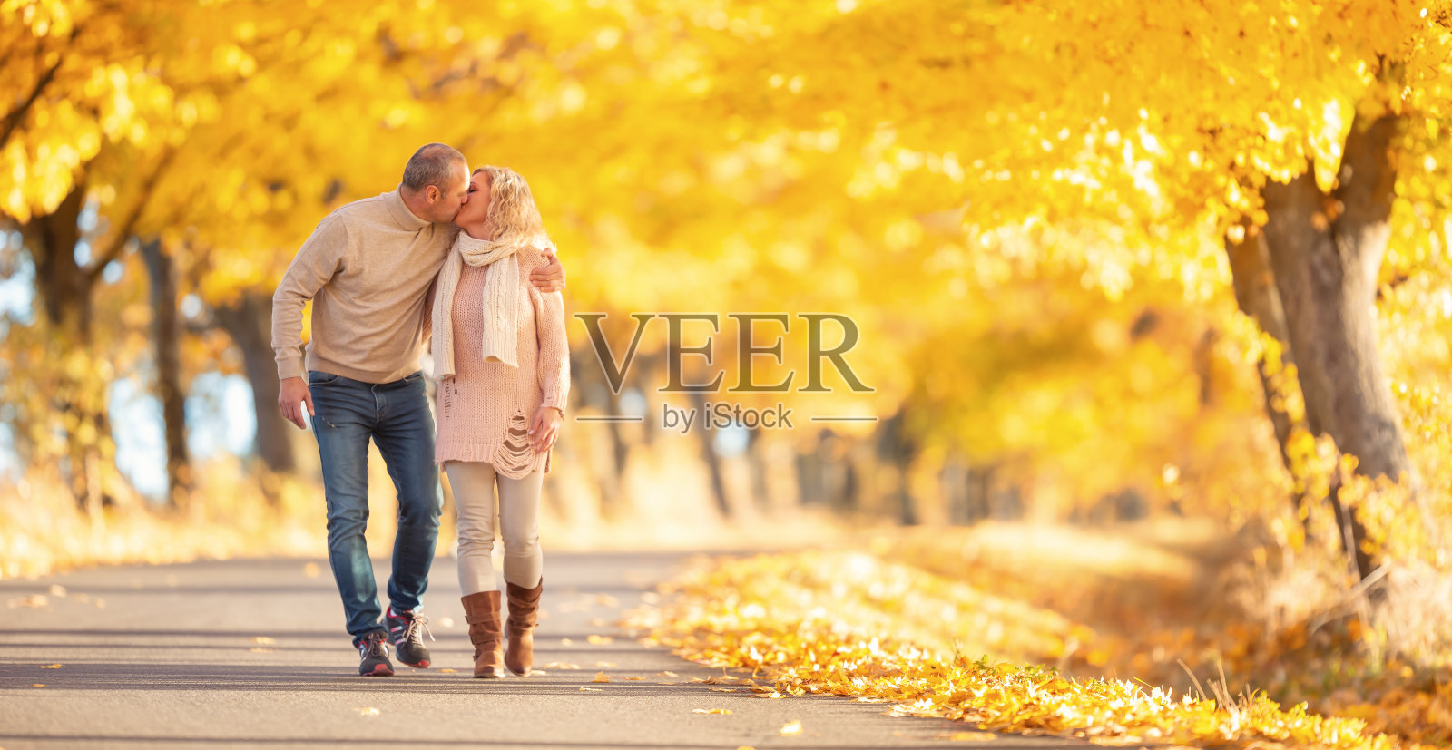 一对热吻的成年夫妇漫步在美丽的秋天公园。照片摄影图片