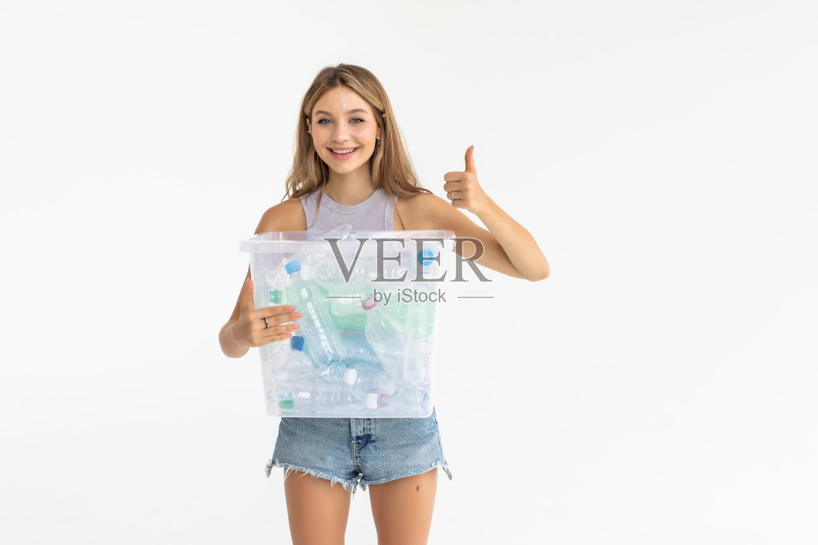 微笑的年轻女子拿着完整的回收箱孤立在白色的背景照片摄影图片
