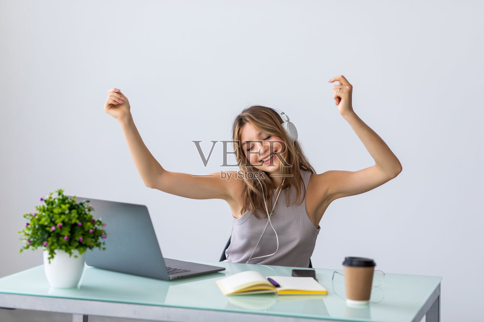 一位年轻的女商人坐在桌旁跳舞。成功快乐的女人庆祝唱片销量。照片摄影图片