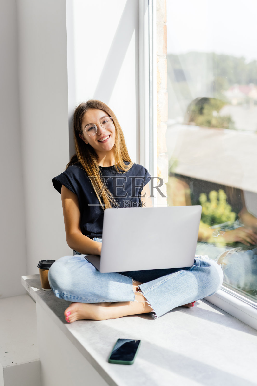 年轻漂亮的女人，窗台上有台笔记本电脑照片摄影图片