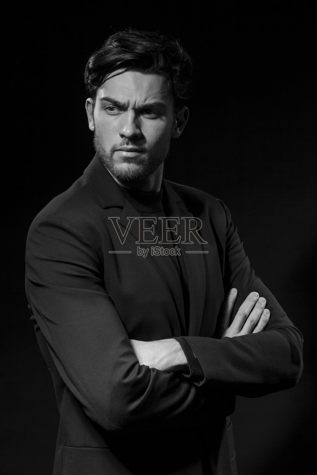 黑白肖像英俊的高加索深色的商人穿着黑色西装与双手合十在黑色工作室背景。垂直的形象定位照片摄影图片