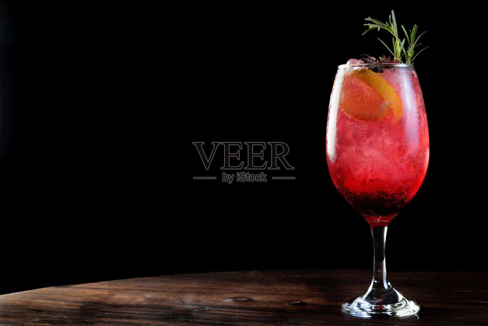 美味和清新的饮料浆果与冰，汤力，柠檬伏特加，金酒，龙舌兰和迷迭香隔离在黑色背景与空间的文字照片摄影图片