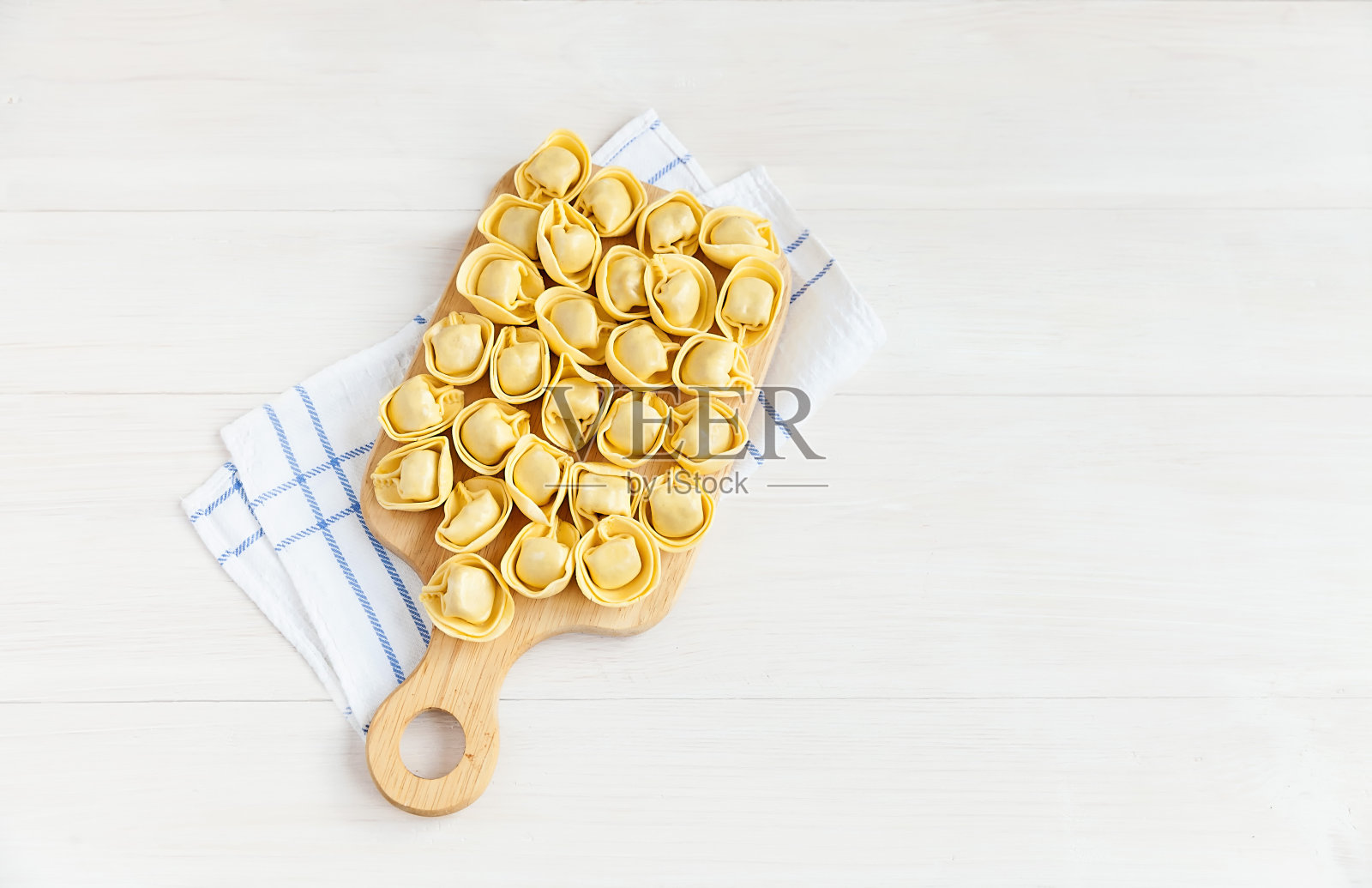 意大利饺子，放在一块木板上烤，上面盖着白餐巾。前视图。照片摄影图片