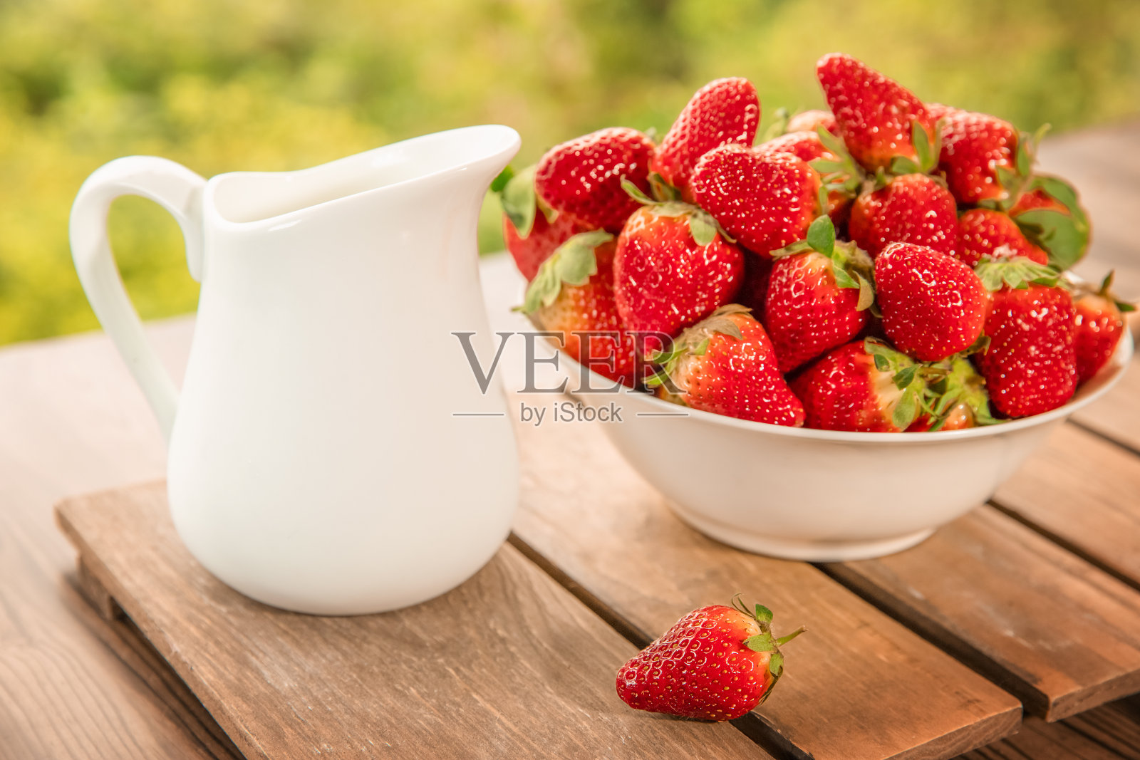 新鲜采摘的有机草莓和牛奶放在木桌上，自然的背景，田园，健康的饮食照片摄影图片