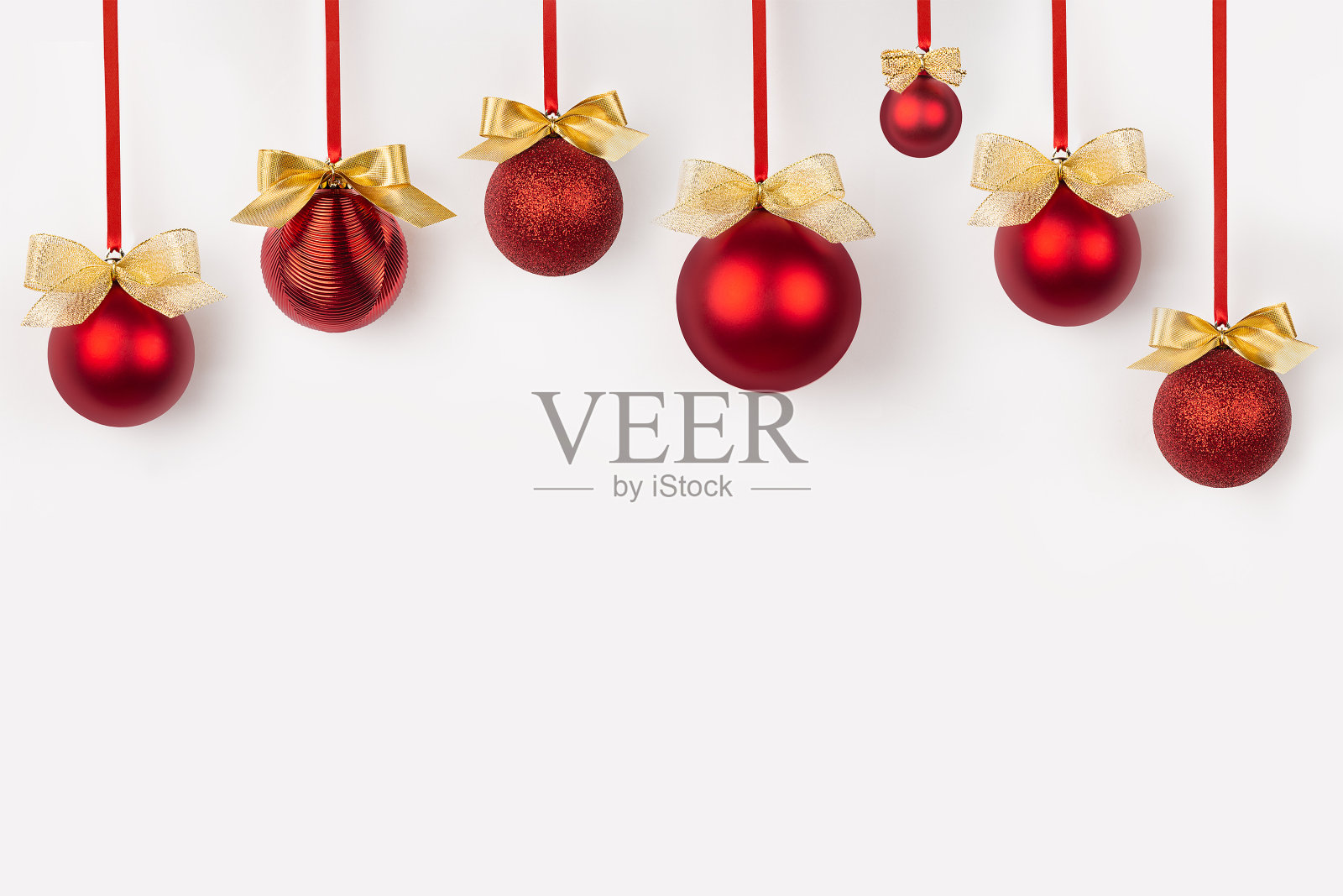 传统的圣诞节背景红色的球，金闪亮的蝴蝶结挂在丝带在白色背景上的图案为海报，传单，卡片，小册子的设计。照片摄影图片