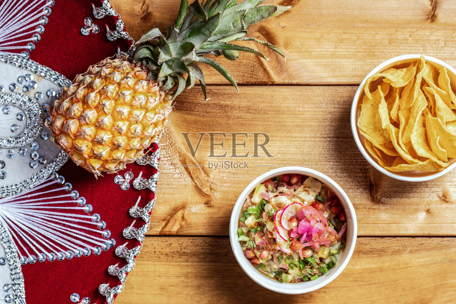 木桌上放着墨西哥玉米片，还有菠萝和墨西哥帽。墨西哥食物的背景。照片摄影图片