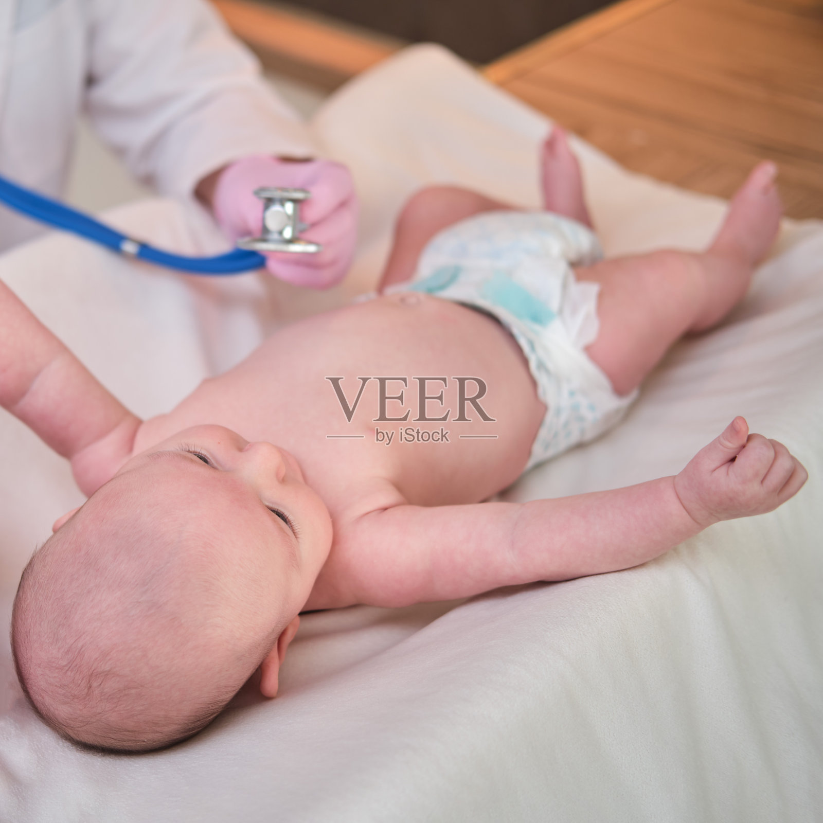 女医生用听诊器听新生儿。护士用听诊器检查孩子的健康状况照片摄影图片