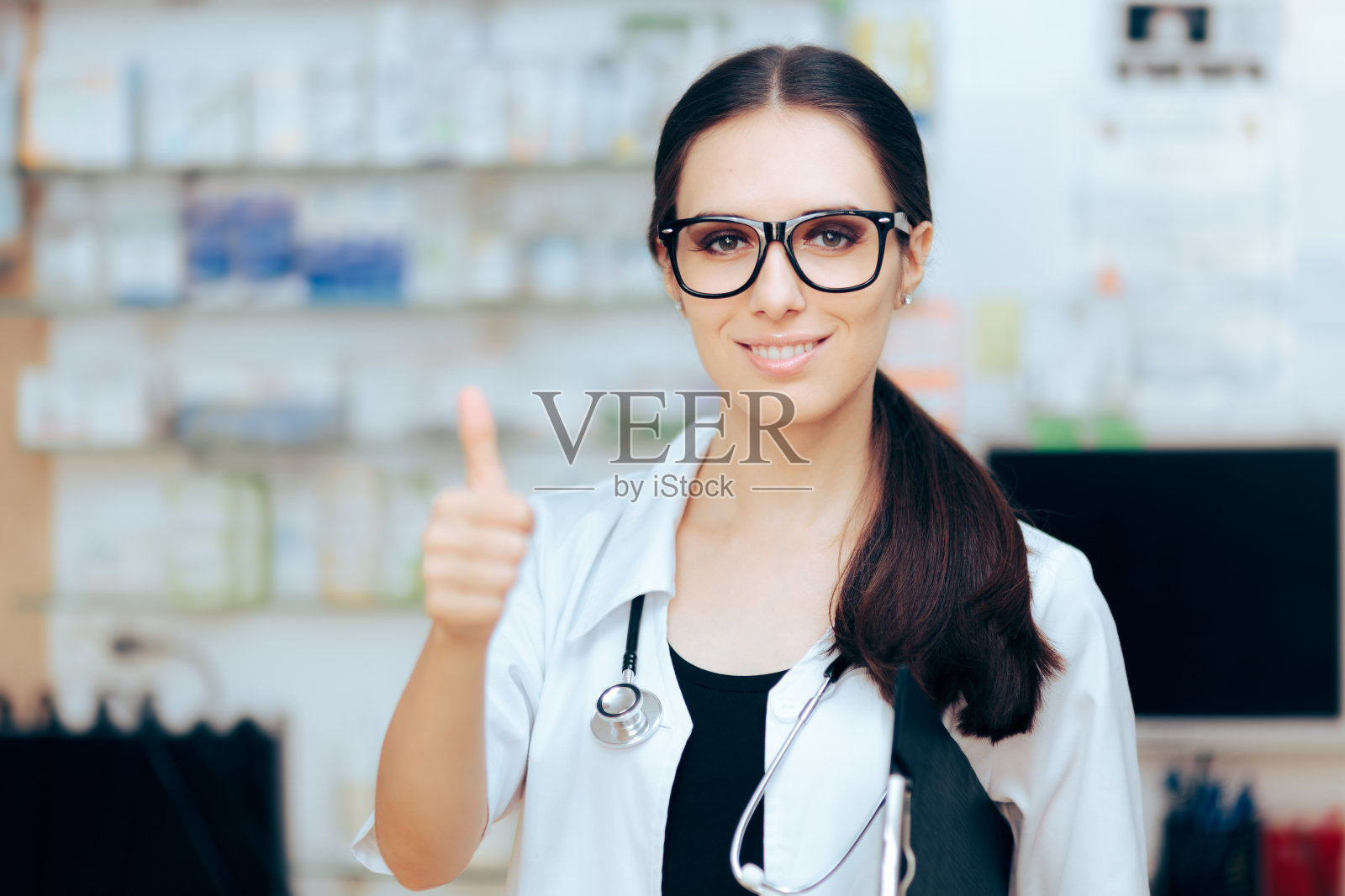 快乐的医生站在她的办公室里做着OK的手势照片摄影图片