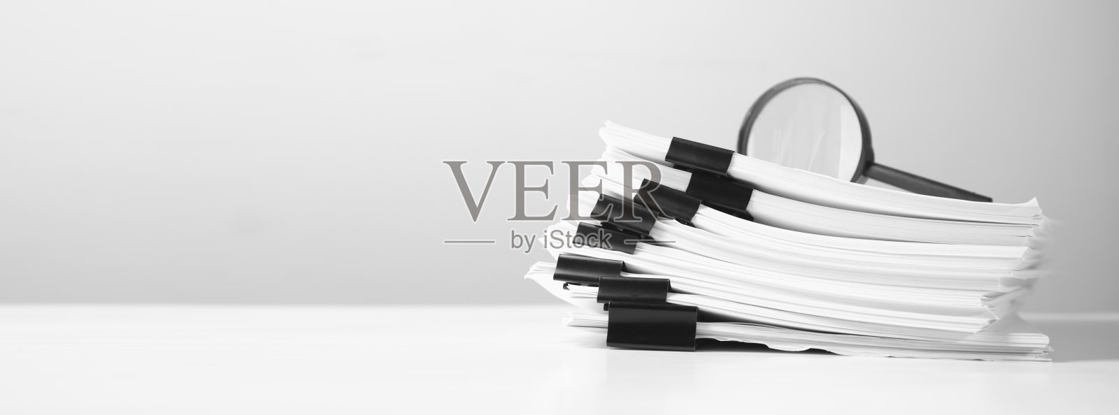 用放大镜把报告文件叠起来。照片摄影图片