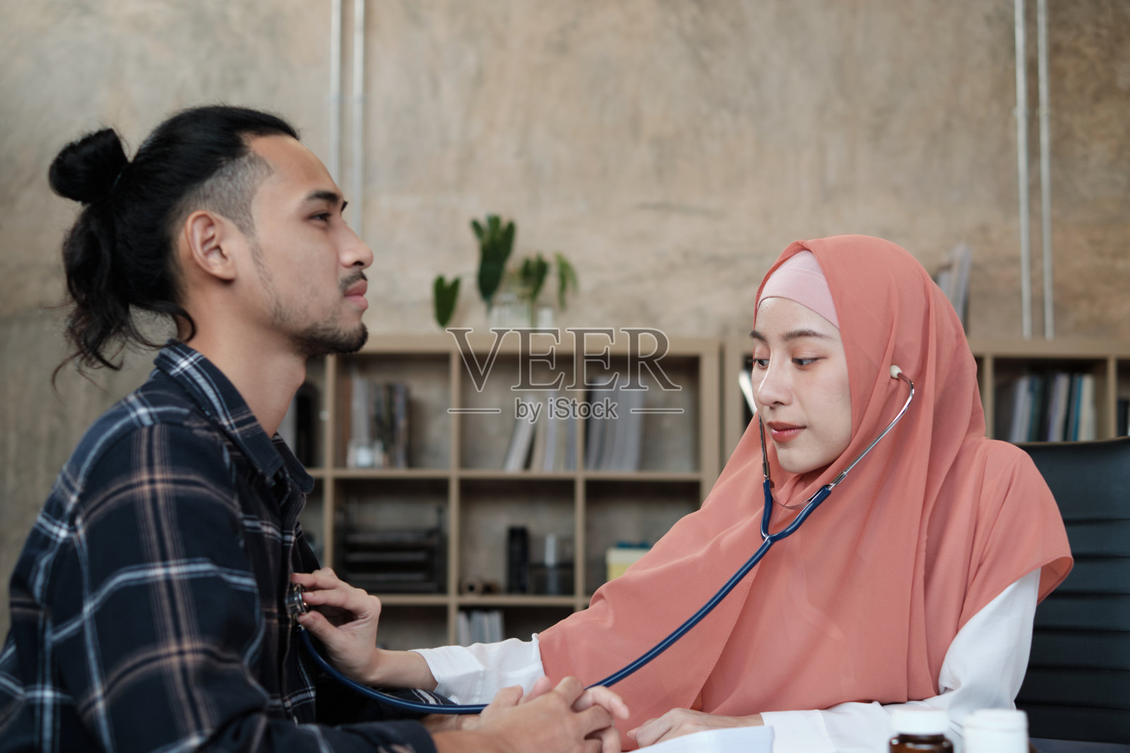 年轻漂亮的女医生正在给一位男病人做健康检查。照片摄影图片