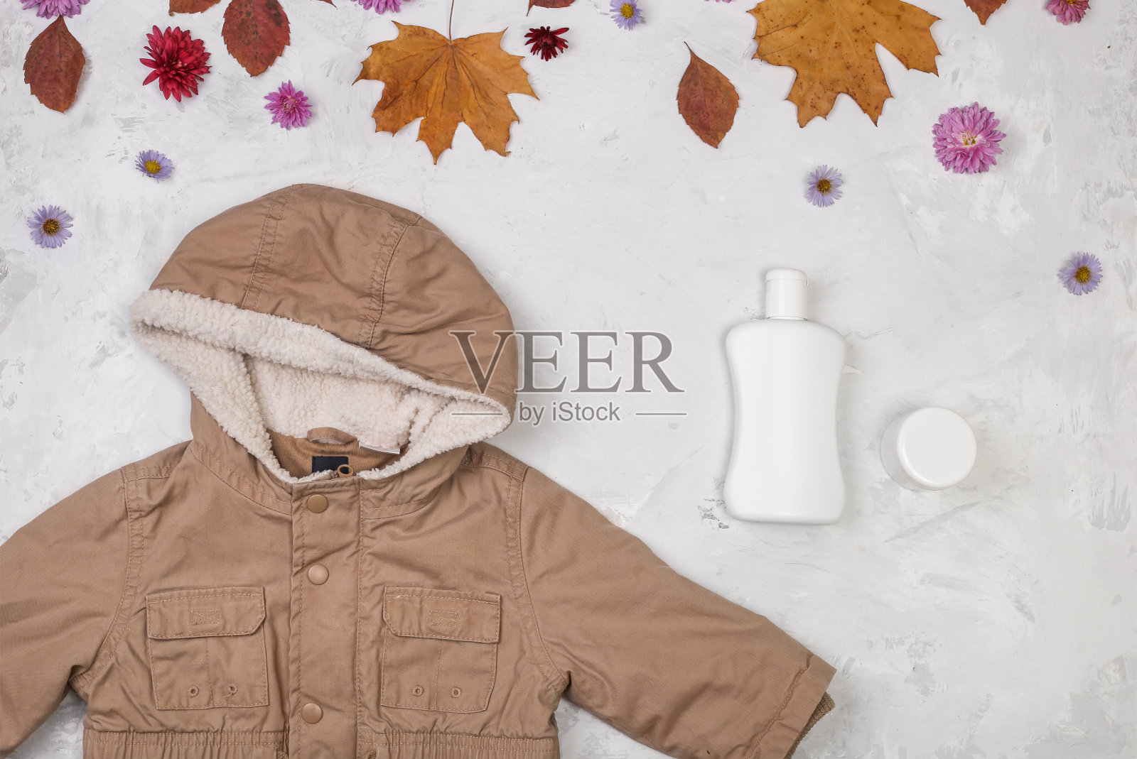 婴儿化妆品冷霜与帆布夹克与石头背景与秋天的树叶。在寒冷季节保护宝宝敏感肌肤照片摄影图片
