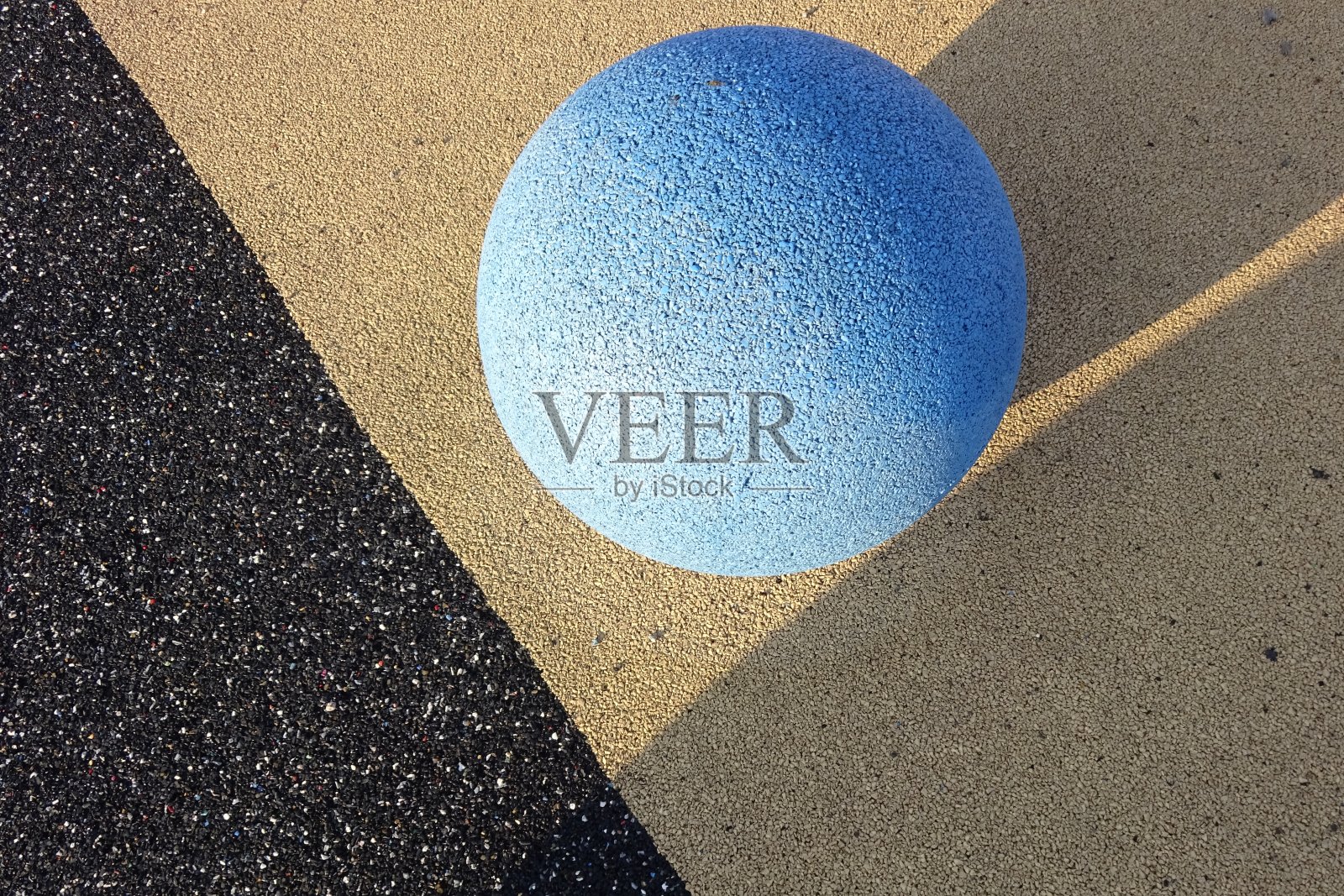 近距离观察浅蓝色石球与纹理纹理表面。黑色或石墨和黄色的对角线人工地板背景。阳光明媚的一天。Reidi tee，塔林，爱沙尼亚照片摄影图片