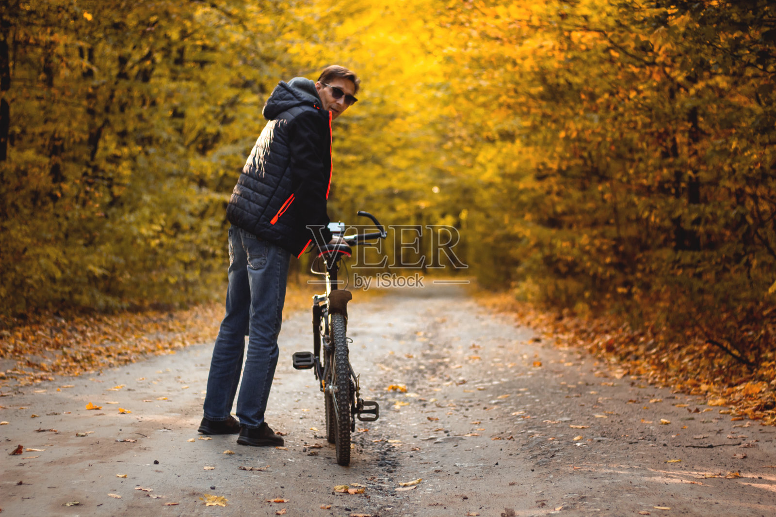 傍晚日落时分，一个骑自行车的人在秋天的森林里照片摄影图片