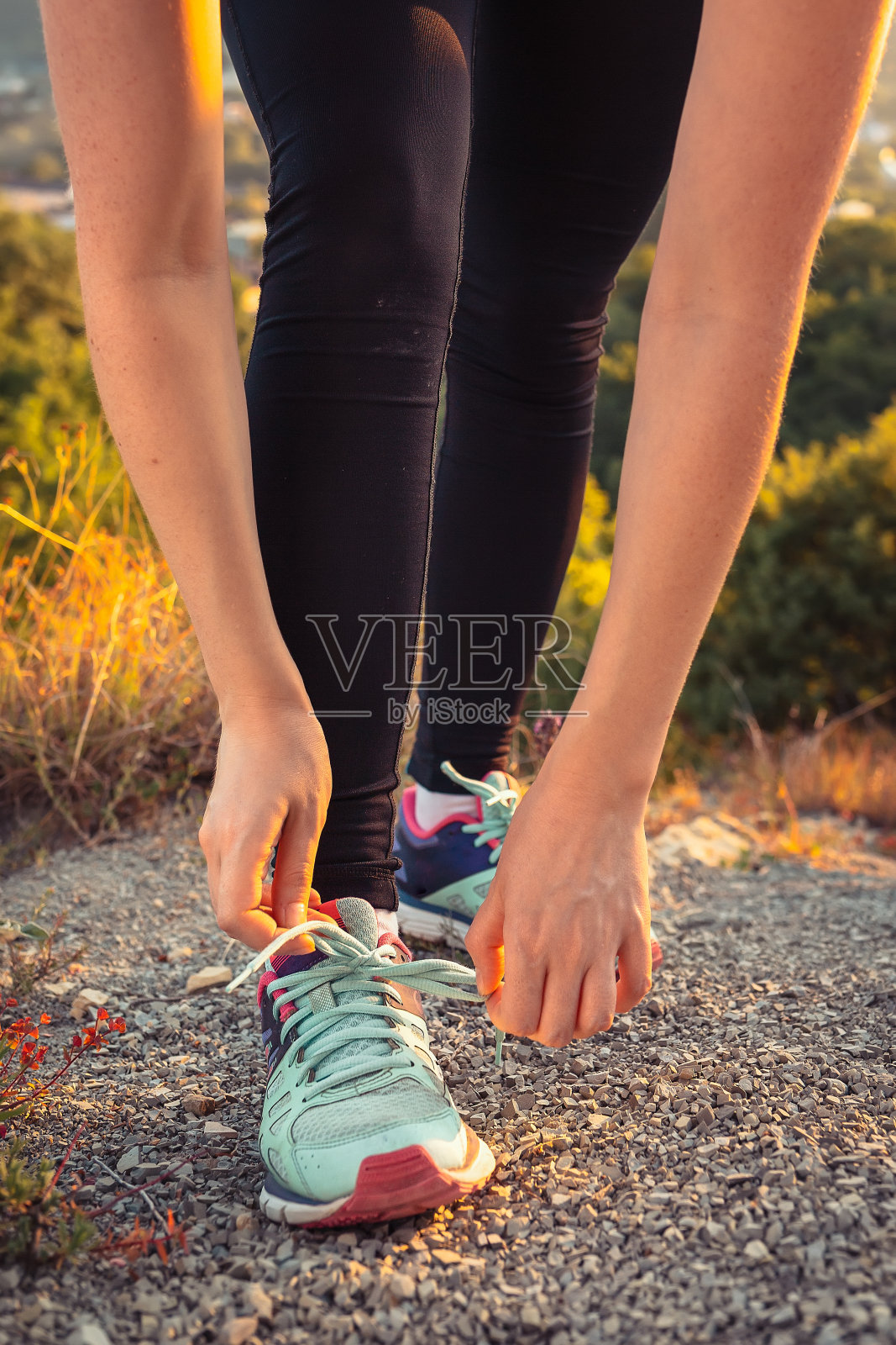 女人在运动鞋上系鞋带。运动、生活方式和训练的概念。垂直方向照片摄影图片