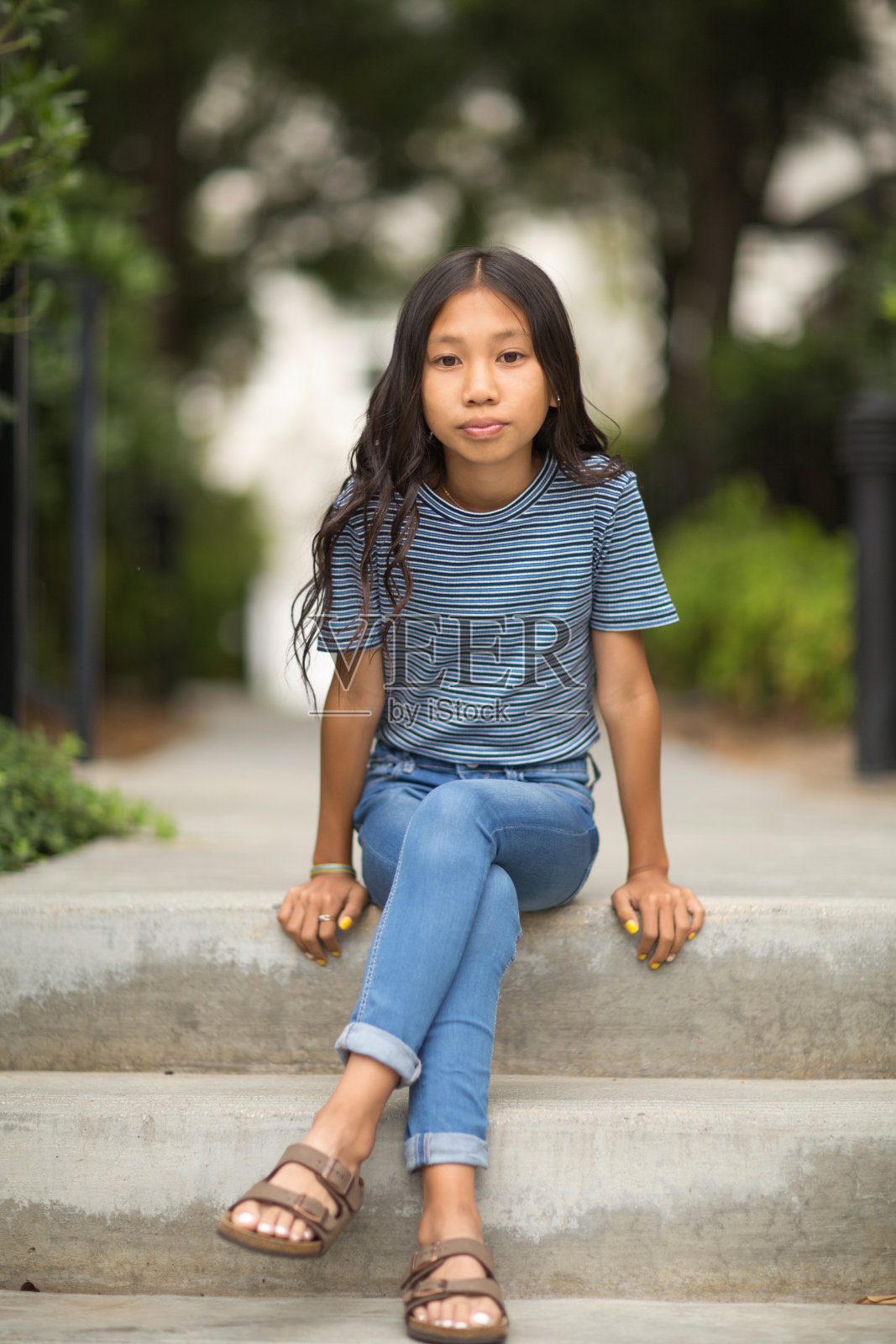 一个年轻的亚洲女孩坐在外面。照片摄影图片