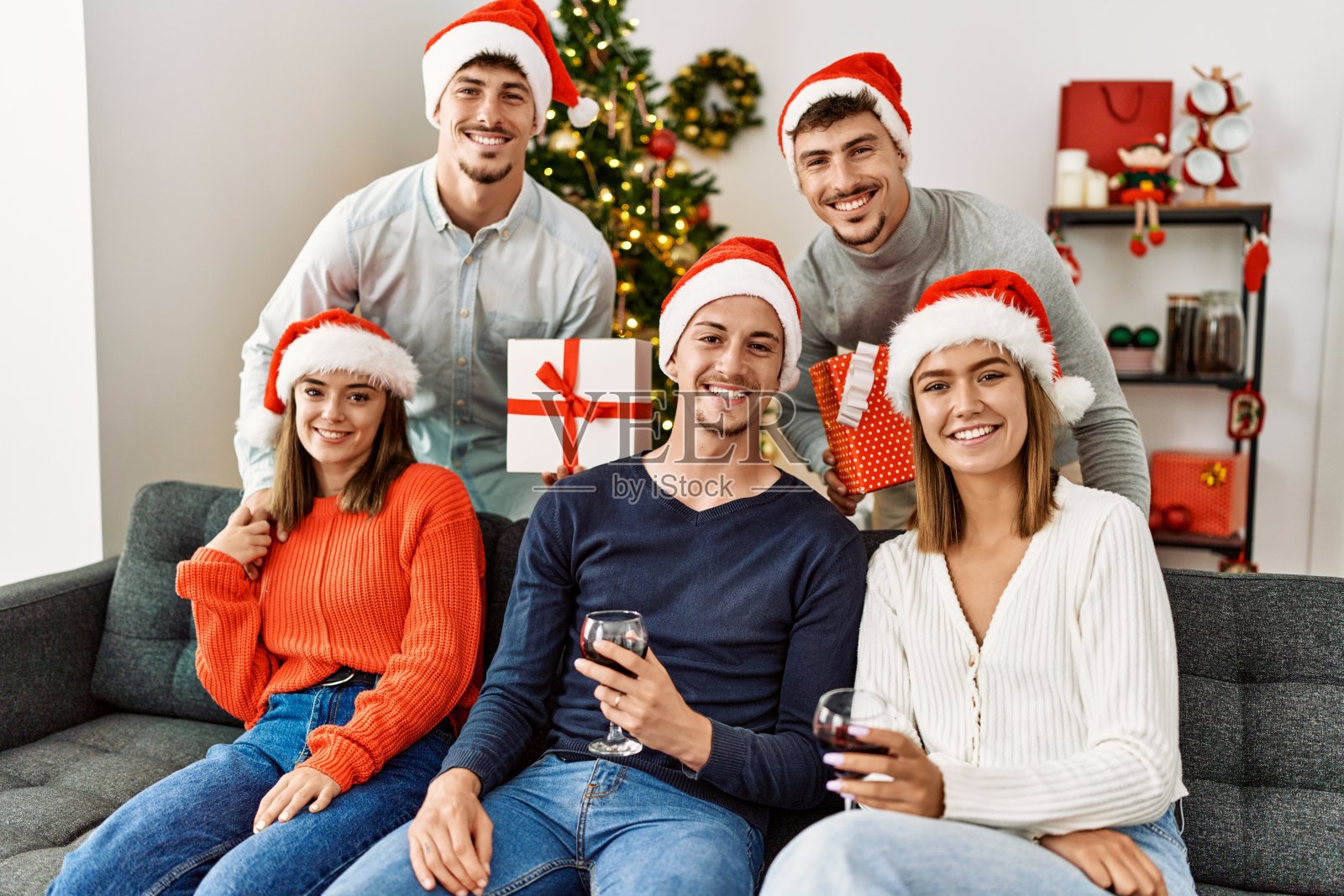 一群年轻人拿着礼物在家里喝酒庆祝圣诞节。照片摄影图片