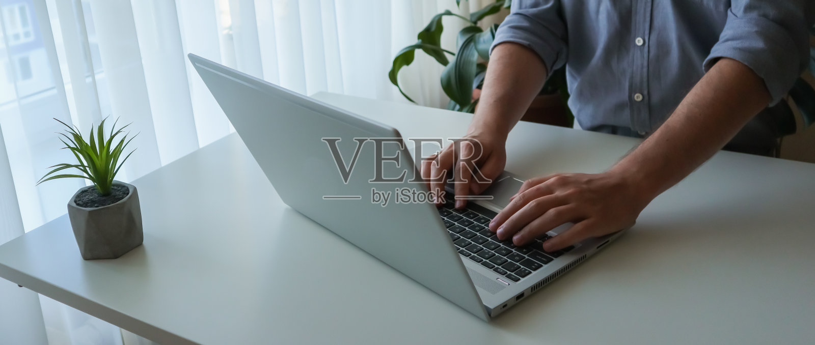 班纳靠近一个正在用笔记本电脑工作的年轻人。在家工作，室内极简主义照片摄影图片