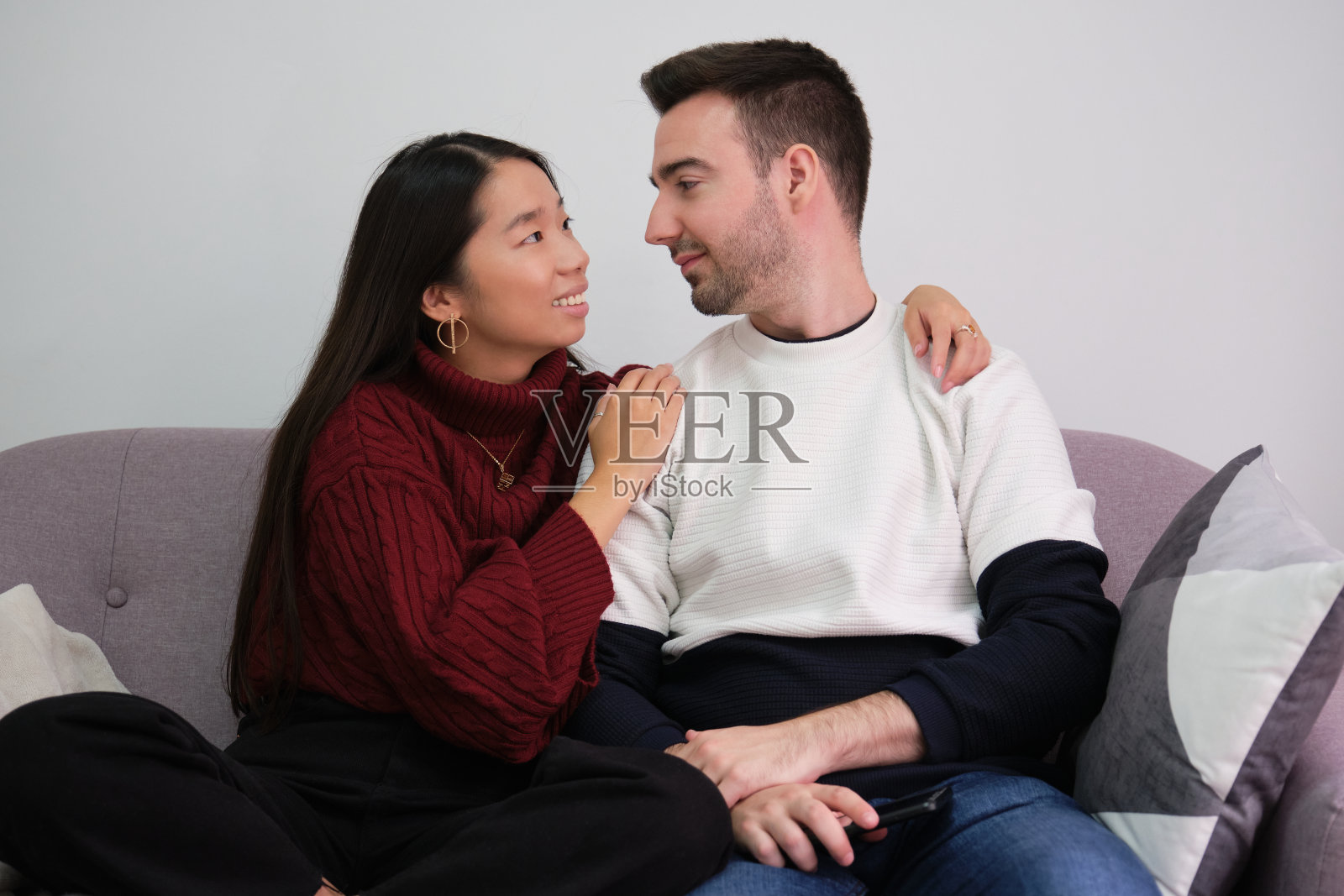 年轻的夫妇在家里的沙发上放松地使用笔记本电脑和微笑。照片摄影图片