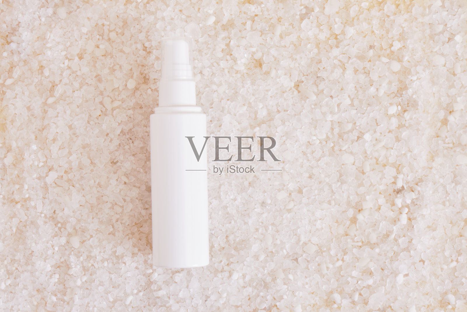 白色的化妆瓶在海盐的背景上照片摄影图片